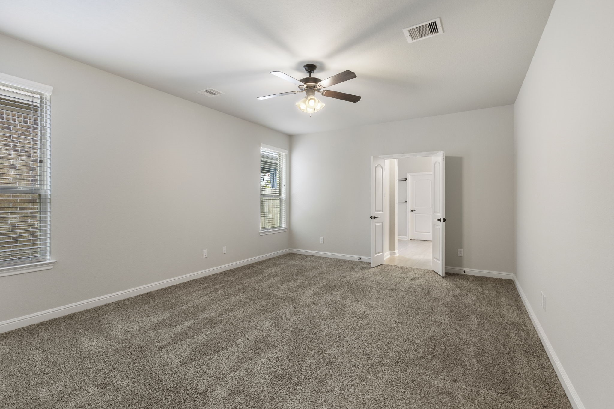 2819 Bradbury Hills Road Spring, TX 77373 - Photo 27 of 50 This spacious primary bedroom offers a serene retreat with plush carpeting, abundant natural light from multiple windows, and elegant double doors leading to a luxurious ensuite.