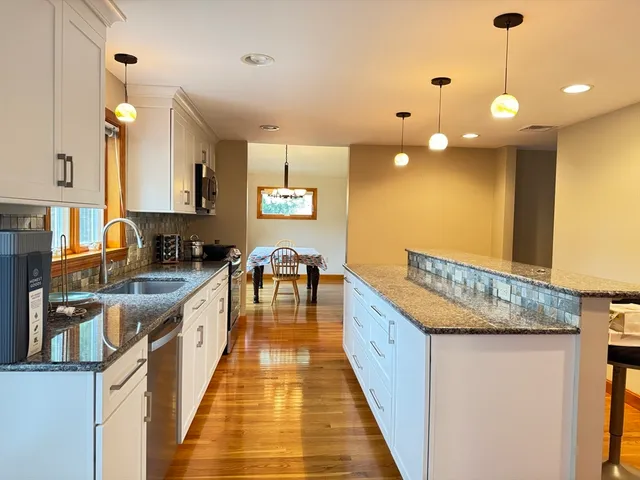 a kitchen with stainless steel appliances granite countertop a stove a sink and a wooden floors