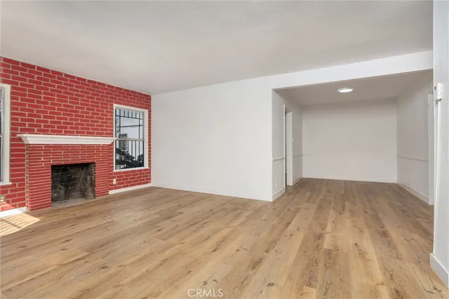 a view of empty room with wooden floor and fireplace