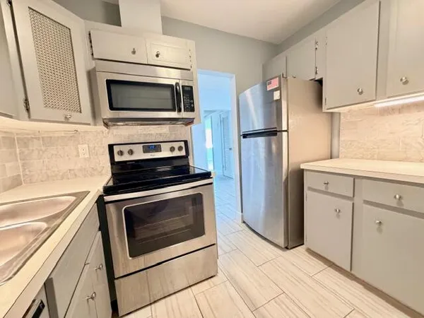 a kitchen with stainless steel appliances white cabinets a stove a microwave and a refrigerator