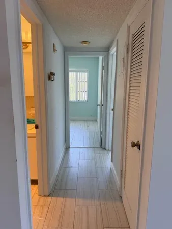 a view of a hallway with wooden floor and a bathroom
