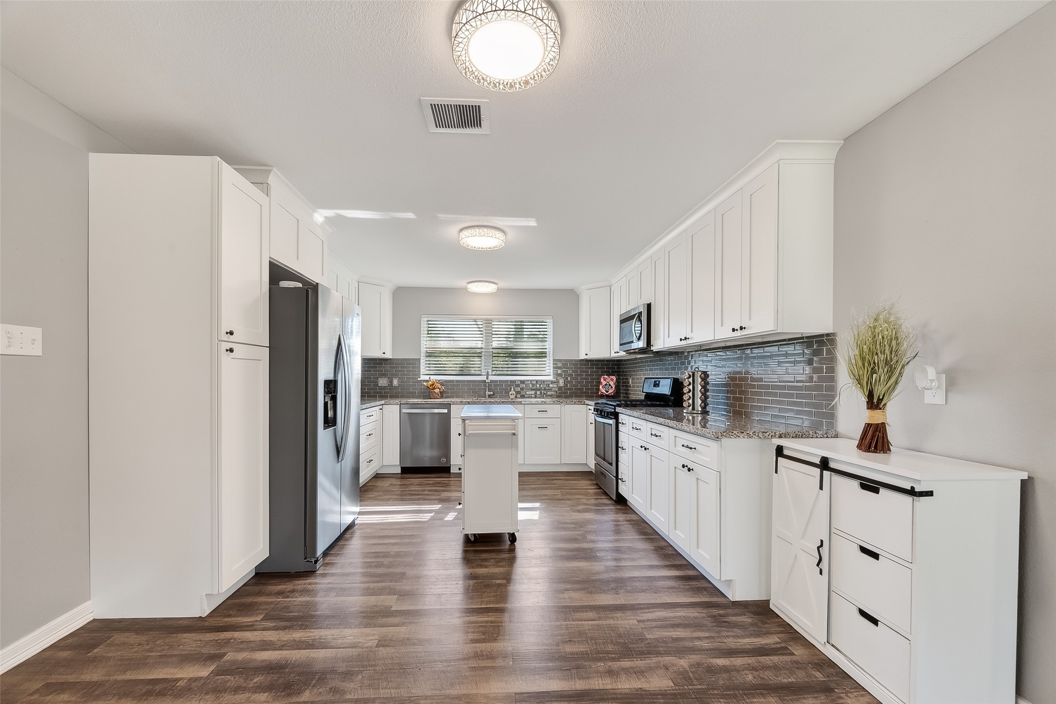 12430 Eiker Road Pearland, TX 77581 - Photo 10 of 41 a kitchen with white cabinets and stainless steel appliances