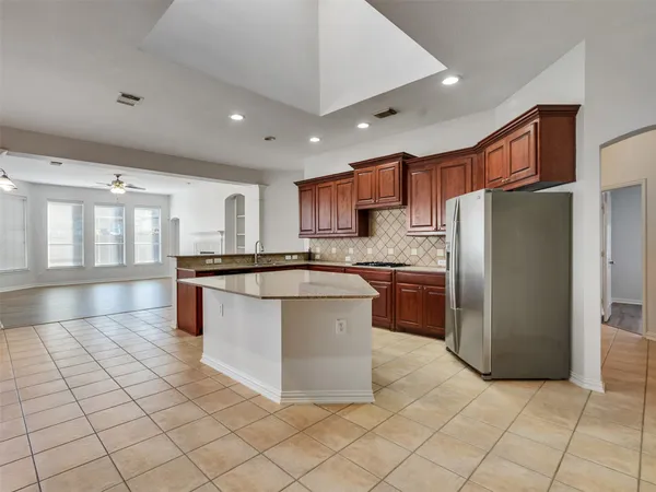 a kitchen with stainless steel appliances granite countertop a refrigerator a sink a stove a microwave and a dining table