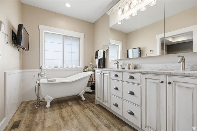 3123 East Riverdale Road Preston, ID 83263 - Photo 23 of 52 Bathroom featuring a clawfoot tub, dual vanity with shaker-style cabinetry, a stone-finish countertop, and wood-finish flooring