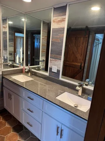 a bathroom with double vanity and a mirror