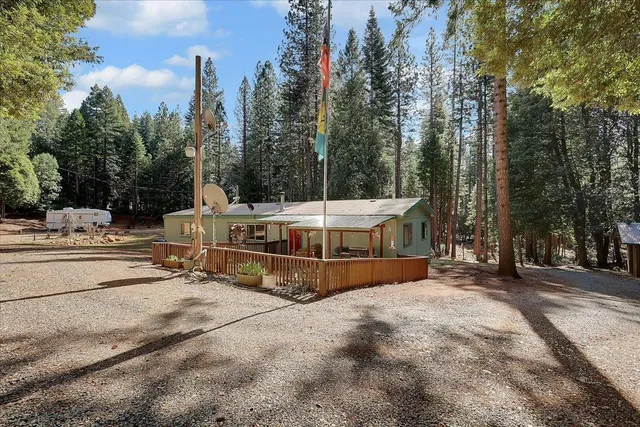 a view of a white house with a big yard and large trees