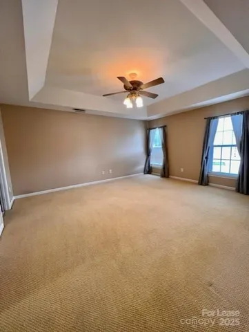 an empty room with windows and chandelier fan