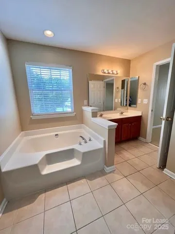 a spacious bathroom with a tub sink and mirror