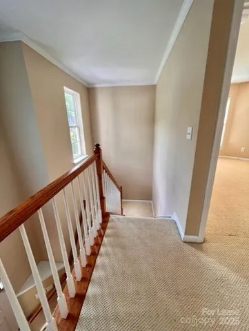 a view of an empty room with wooden floor and stairs