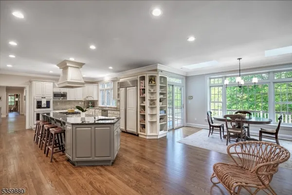 a living room with stainless steel appliances granite countertop furniture wooden floor and a large window
