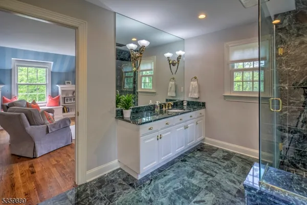 a spacious bathroom with a granite countertop sink a mirror and shower