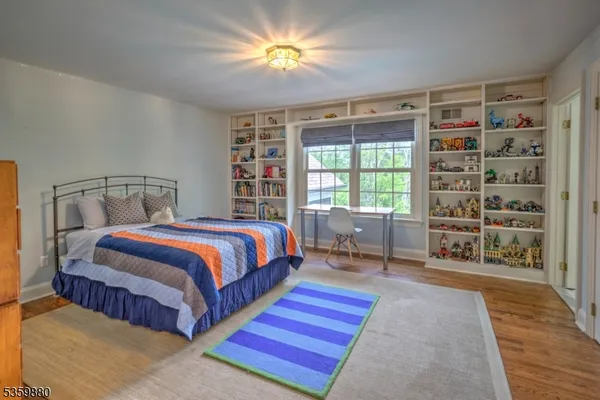a spacious bedroom with a bed a table and a bookshelf with wooden floor