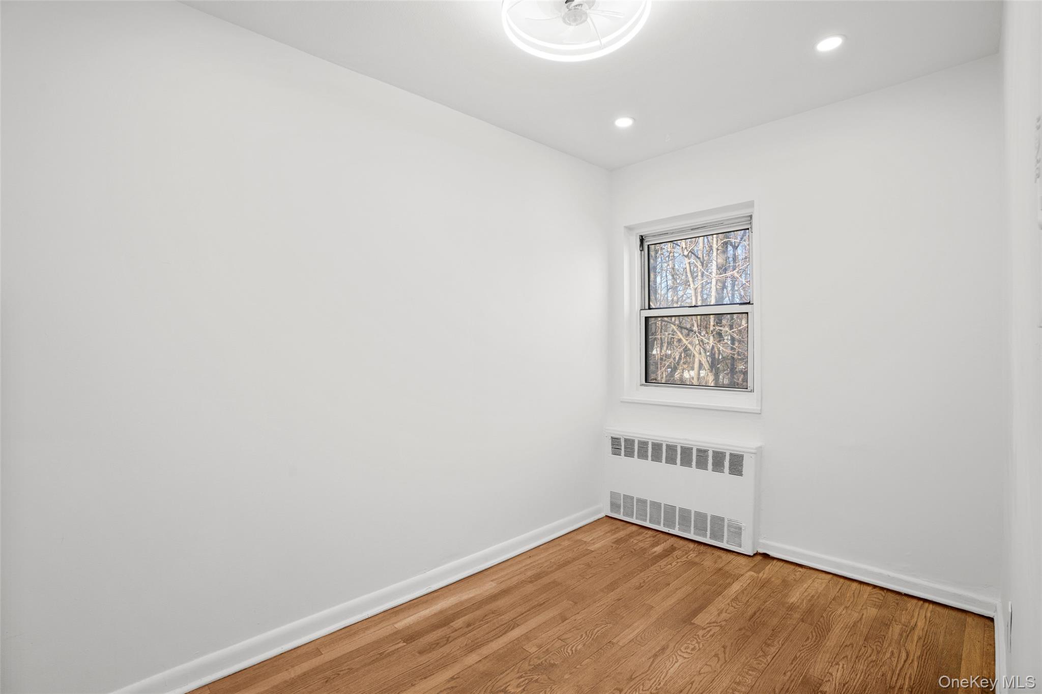 179 Drake Avenue, Unit 2J New Rochelle, NY 10805 - Photo 7 of 16 Spare room featuring radiator heating unit, light wood-style flooring, and recessed lighting