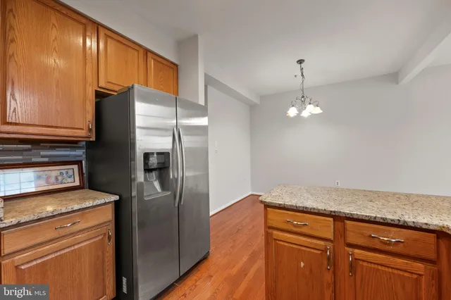 a kitchen with granite countertop stainless steel appliances a refrigerator stove and cabinets