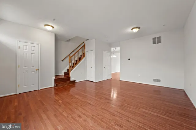 a view of empty room with wooden floor and stairs