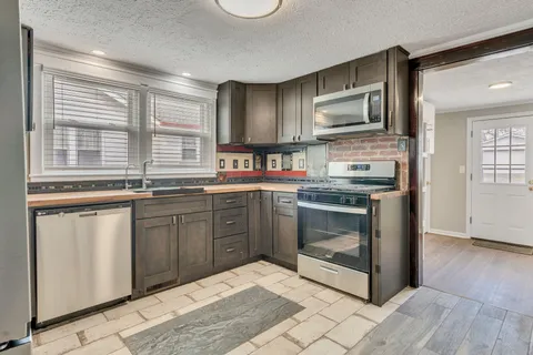 a kitchen with stainless steel appliances granite countertop a stove a sink and a microwave