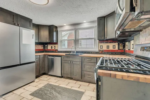 a kitchen with stainless steel appliances a stove a sink a refrigerator and a microwave