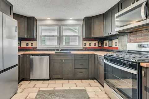 a kitchen with stainless steel appliances granite countertop a stove a sink and a microwave