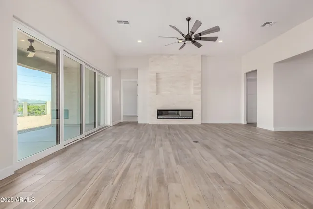 a view of an empty room with a window and wooden floor
