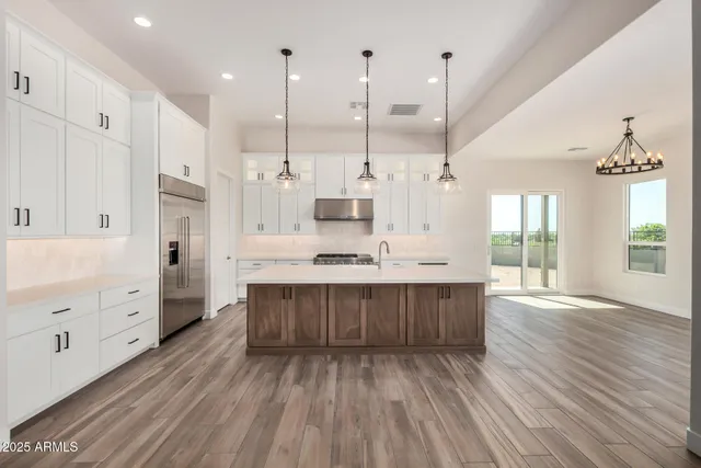 a large kitchen with stainless steel appliances granite countertop a large center island attached withe living room