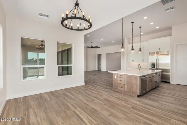 a large kitchen with stainless steel appliances granite countertop a stove a sink dishwasher and a dining table with wooden floor