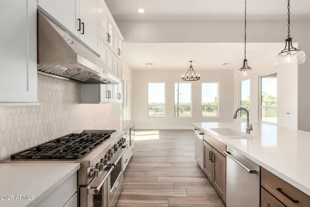 a kitchen with stainless steel appliances granite countertop a sink a center island a stove and a wooden floor