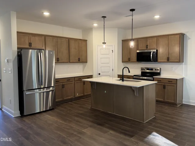 a kitchen with kitchen island granite countertop a sink a counter and stainless steel appliances