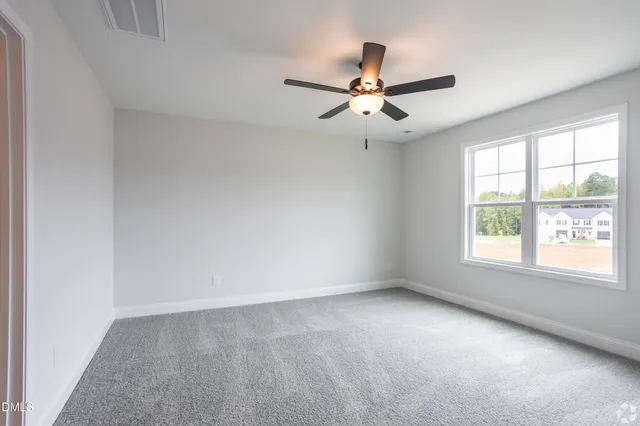 an empty room with windows and fan