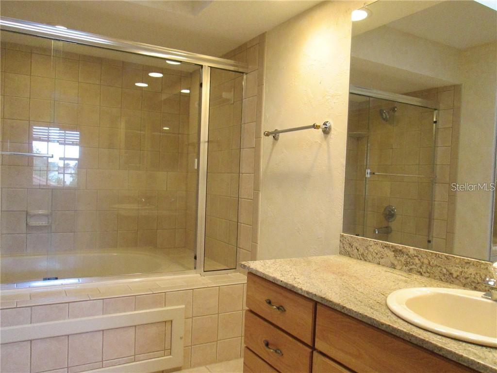 14873 Feather Cove Road Clearwater, FL 33762 - Photo 21 of 25 a bathroom with a granite countertop sink a mirror and a bathtub