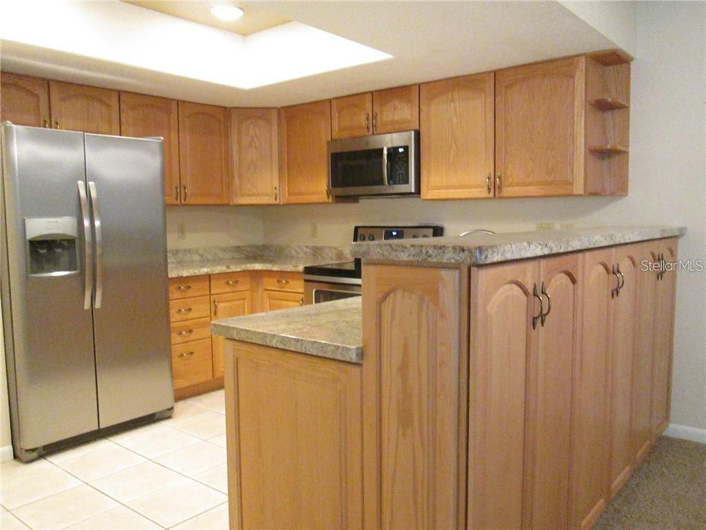 14873 Feather Cove Road Clearwater, FL 33762 - Photo 8 of 25 a kitchen with stainless steel appliances granite countertop a refrigerator a stove a sink and dishwasher