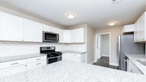 a kitchen with granite countertop a refrigerator stove top oven and sink