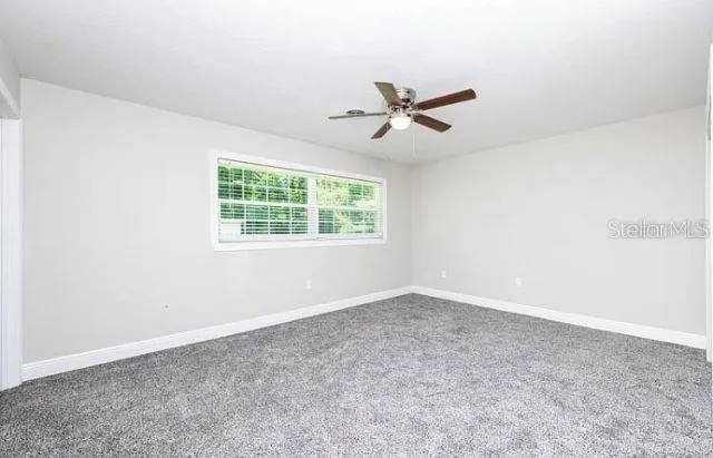 an empty room with a window and a fan