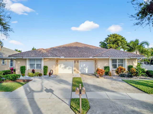 a view of a white house with a small yard and a large tree