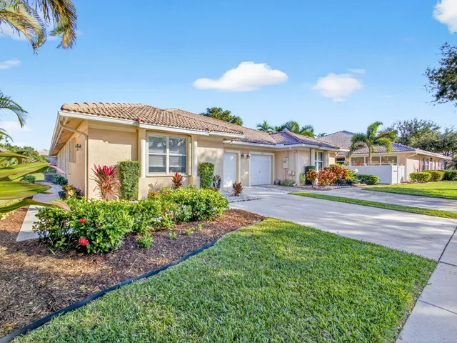 a front view of a house with a big yard and potted plants