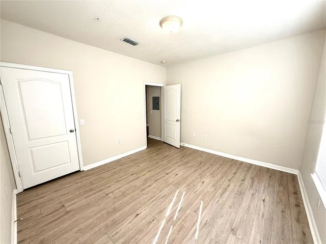 an empty room with wooden floor and cabinet