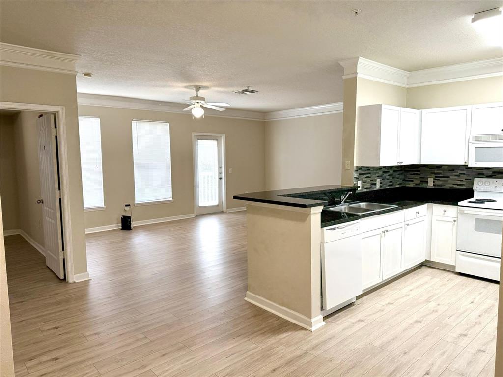 8842 Villa View Circle, Unit 3 Orlando, FL 32821 - Photo 5 of 21 a kitchen with granite countertop a stove a sink and a refrigerator