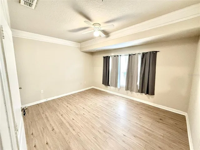 an empty room with wooden floor and a ceiling fan