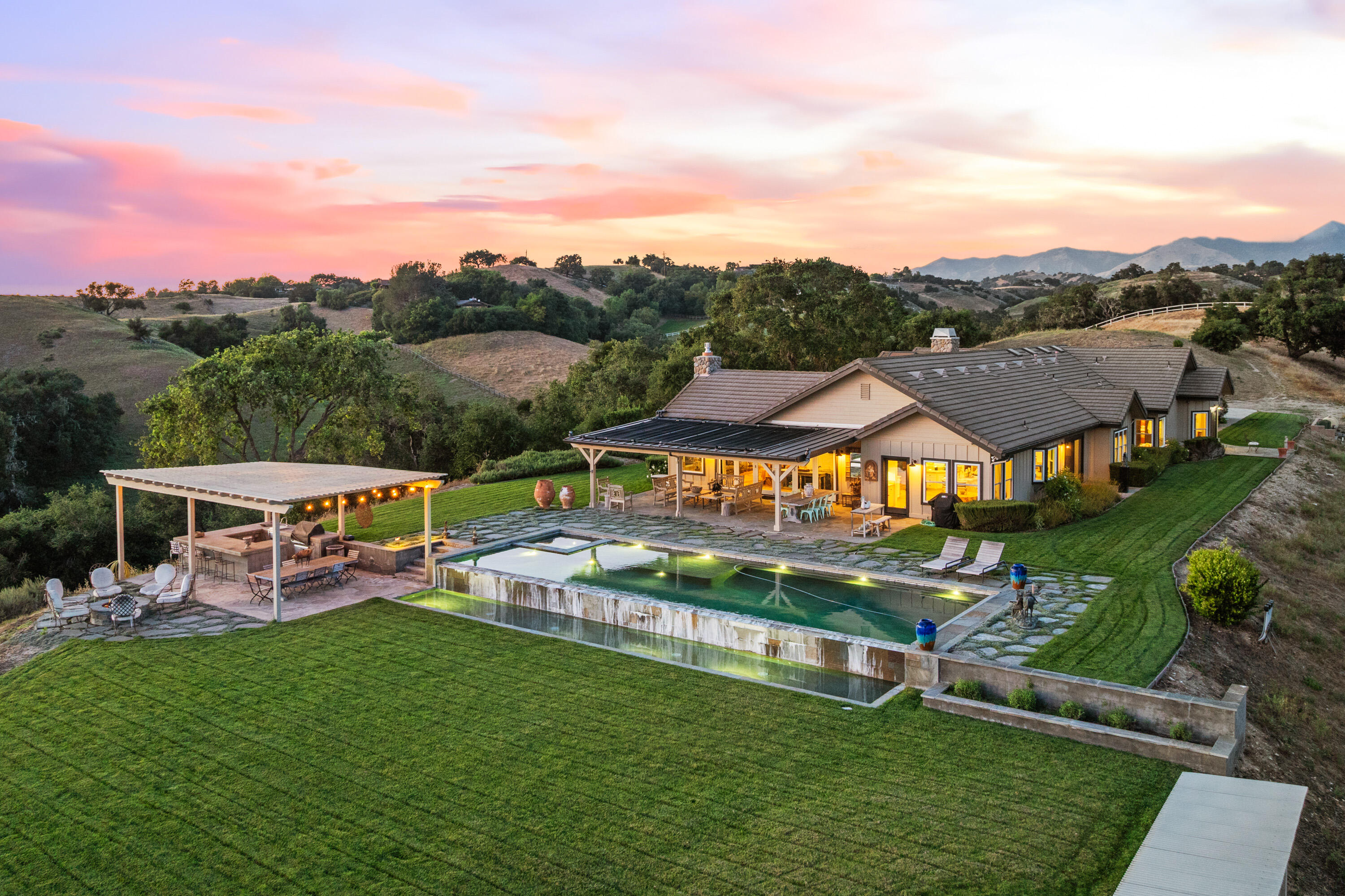 an aerial view of a house with swimming pool garden and mountain view in back