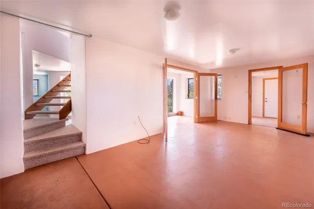 a view of an empty room with wooden floor and stairs