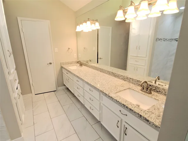a spacious bathroom with a granite countertop sink a mirror and a shower