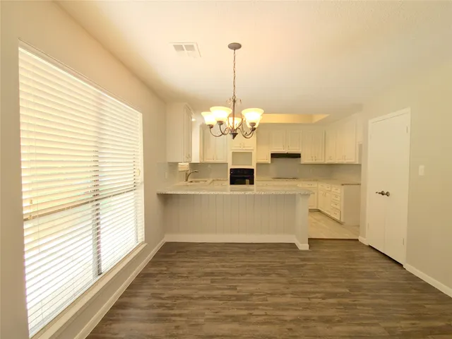 a view of a kitchen with kitchen island a sink wooden floor and a chandelier