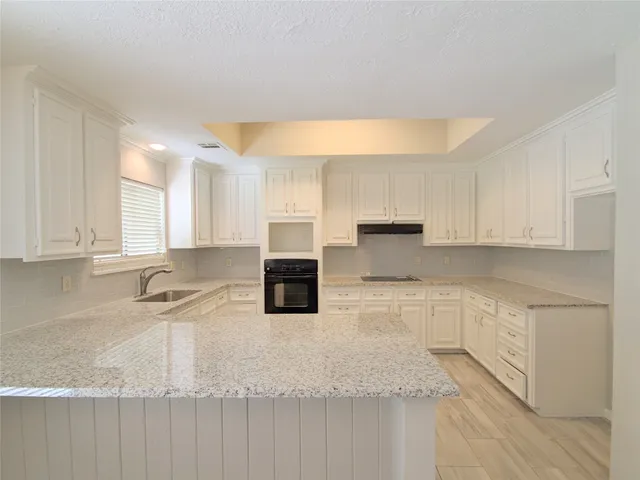 a kitchen with granite countertop a sink a stove and cabinets