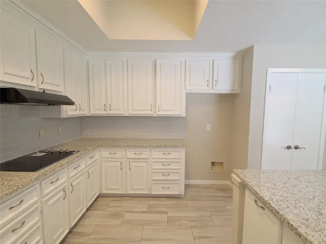a kitchen with granite countertop white cabinets and stainless steel appliances