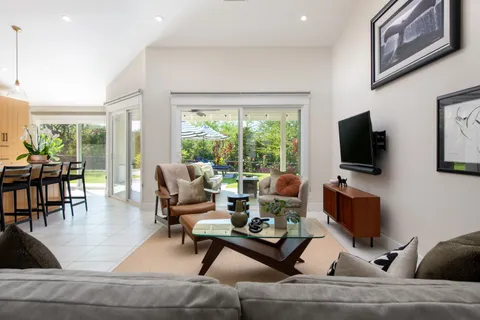 a living room with furniture floor to ceiling window and a flat screen tv