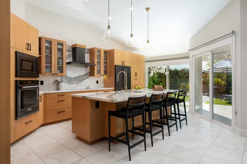 a open kitchen with stainless steel appliances granite countertop a stove top oven a sink dishwasher a dining table and chairs with wooden floor