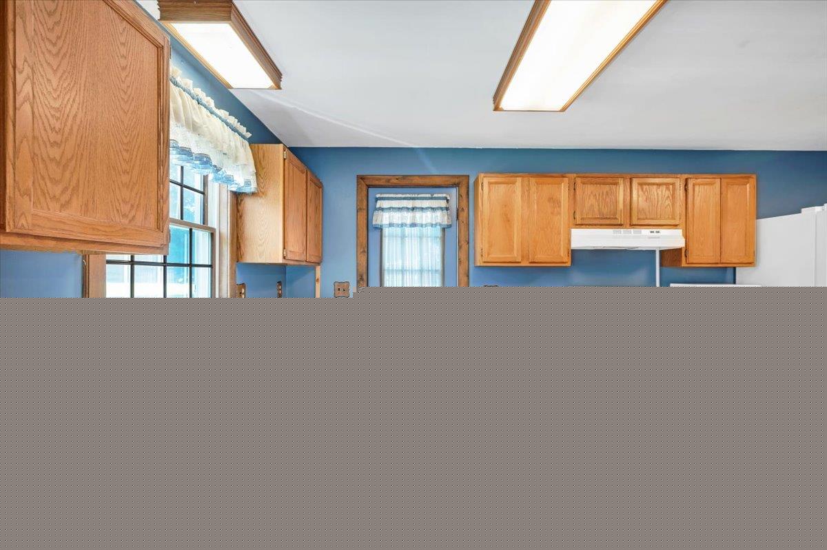 980 West Predmore Road Oakland, MI 48363 - Photo 6 of 11 Kitchen featuring extensive wood cabinetry, double basin stainless steel sink, white electric range with overhead vent, and tiled flooring