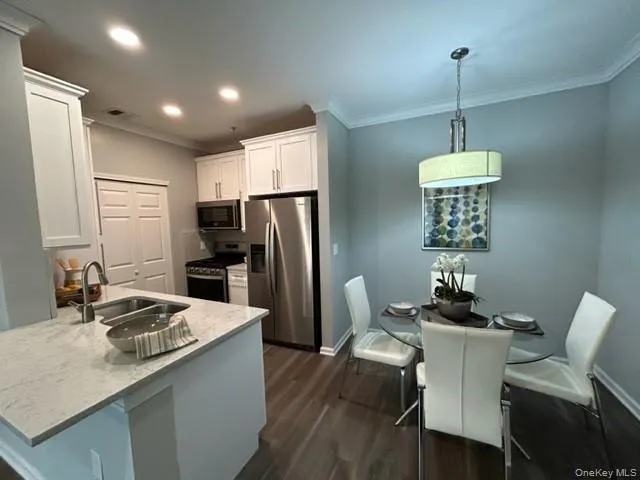 a kitchen with stainless steel appliances granite countertop a dining table chairs refrigerator and sink