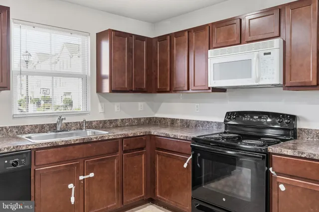 a kitchen with granite countertop a sink stove and cabinets