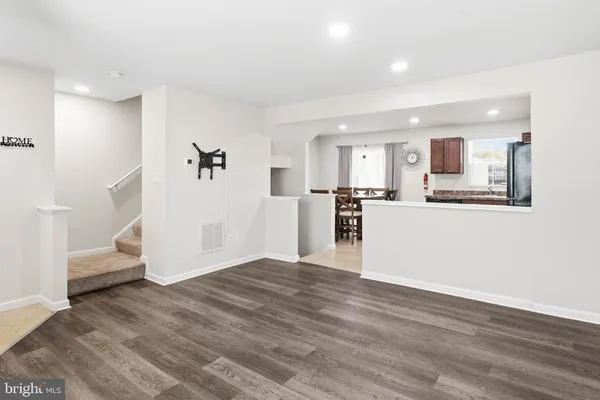 a view of a kitchen and an empty room with wooden floor and a kitchen