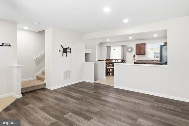 a view of a kitchen and an empty room with wooden floor and a kitchen